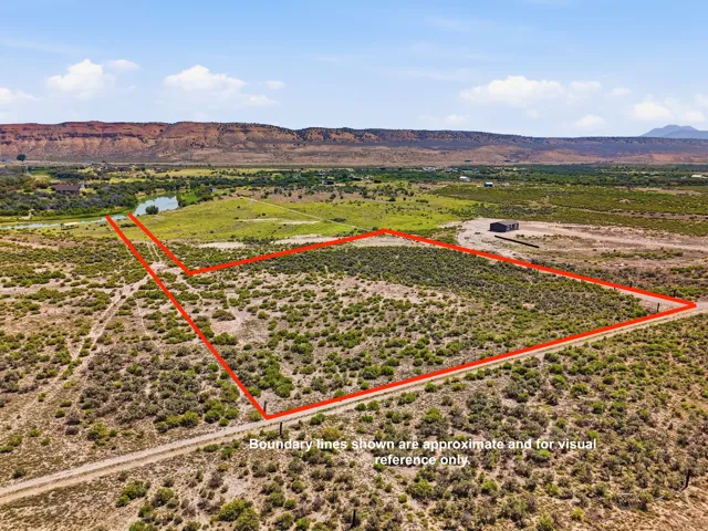 Expansive land parcel with surrounding natural terrain, distant mountain backdrop, and a water feature