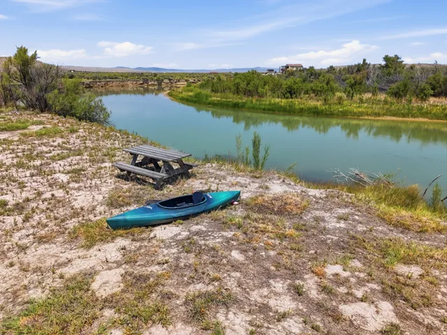 Riverfront property featuring a winding river, varied vegetation, and a wooden picnic table