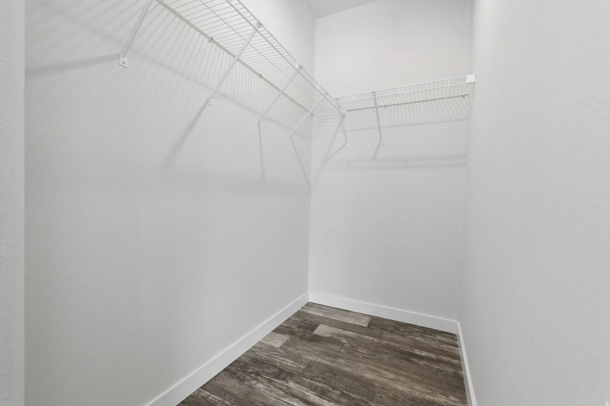 Walk-in closet with wire shelving and wood-finish flooring