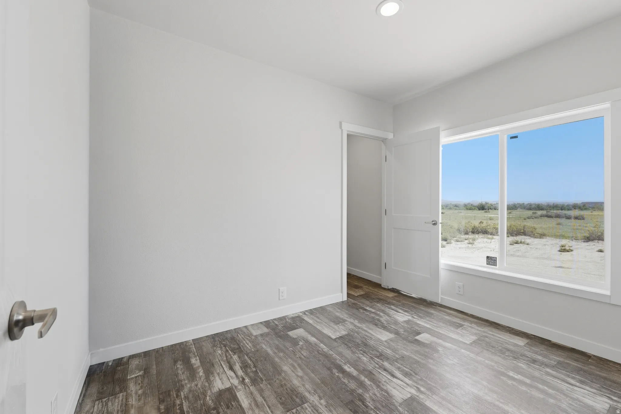 Recessed lighting, wood-finish flooring, white trim, and a large window