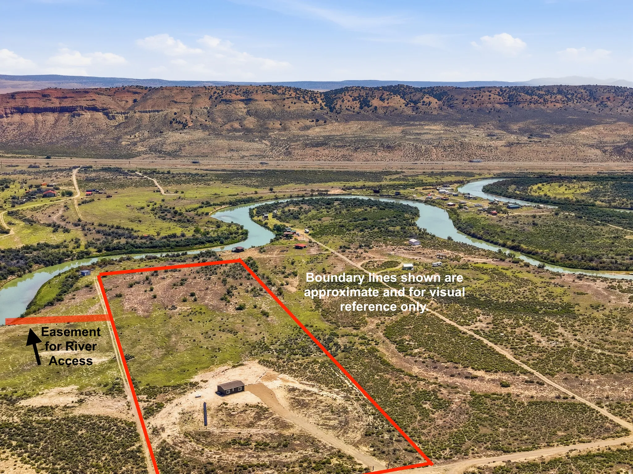 Expansive land parcel featuring natural terrain, a winding river, and distant mountainous backdrop