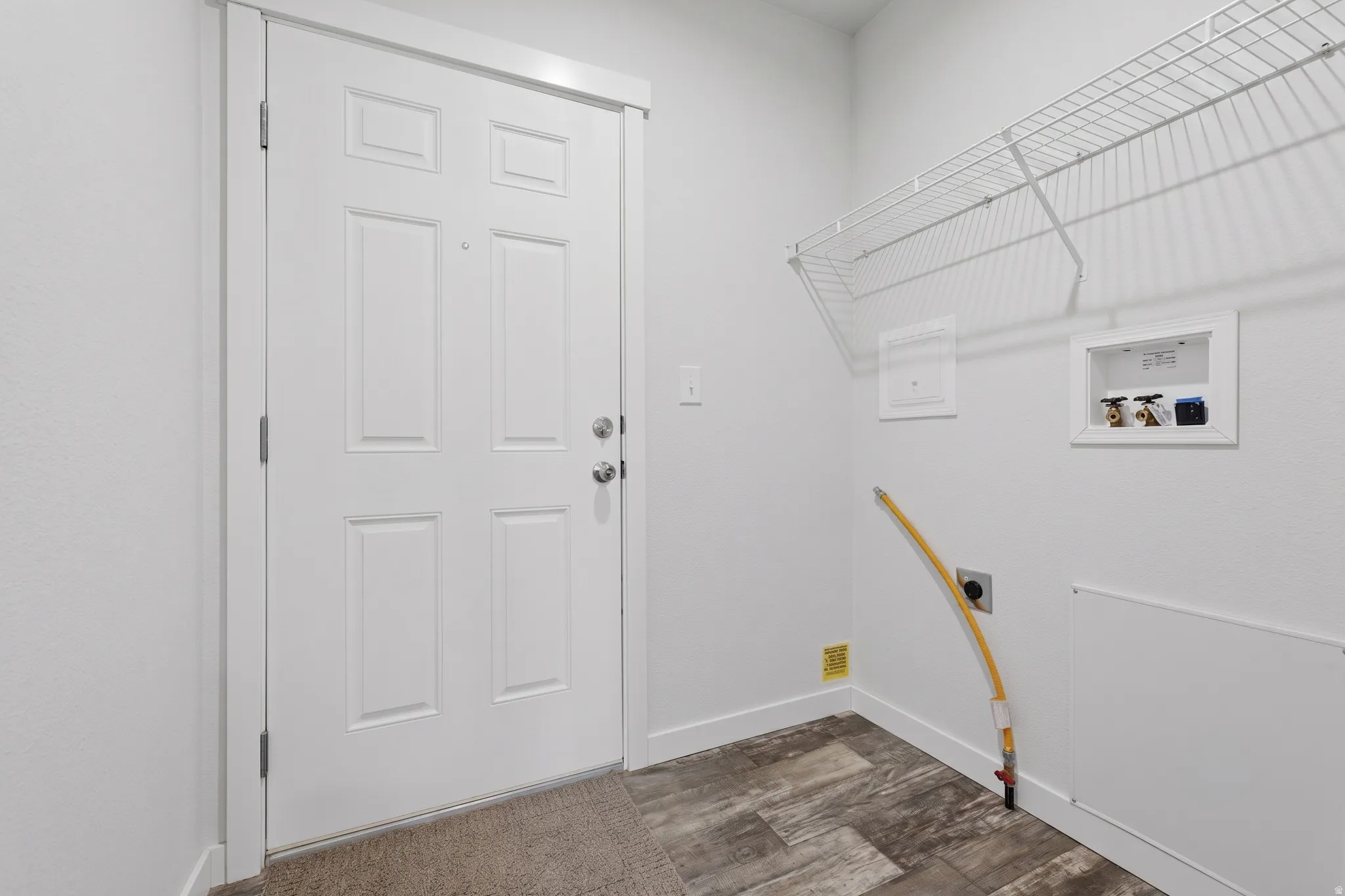 Laundry area featuring wire shelving, utility hookups, and wood-finish flooring
