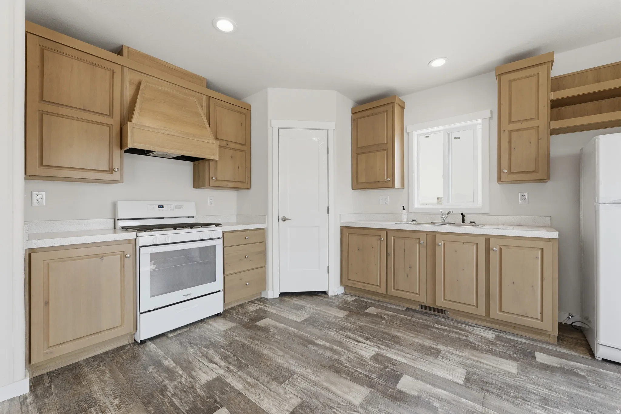 Kitchen featuring wood-finish cabinetry, white countertops, built-in range, and wood-finish flooring