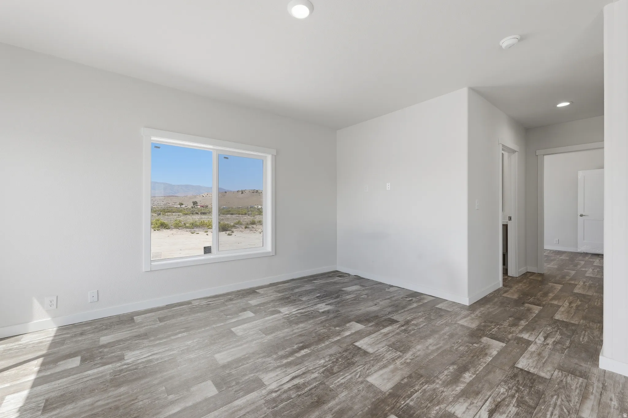 Wood-finish flooring, recessed lighting, and a window with desert scenery