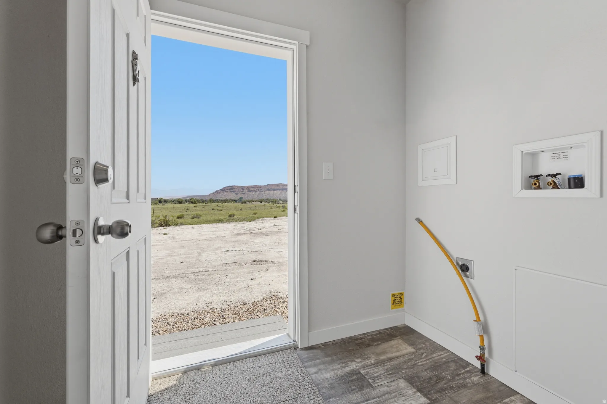 Utility space featuring wall-mounted hookups, wood-finish flooring, and a solid exterior door