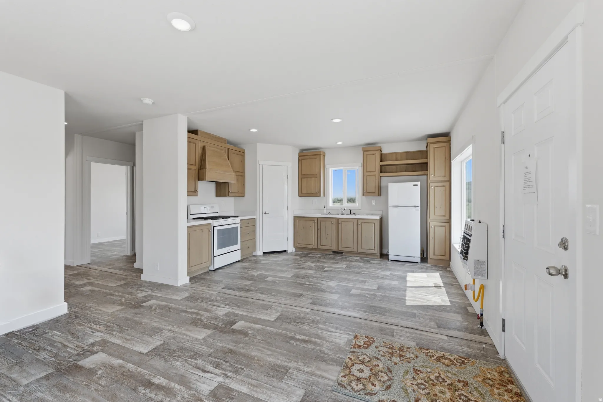 Open-concept living area featuring wood-finish flooring, recessed lighting, and a kitchen with light wood cabinetry