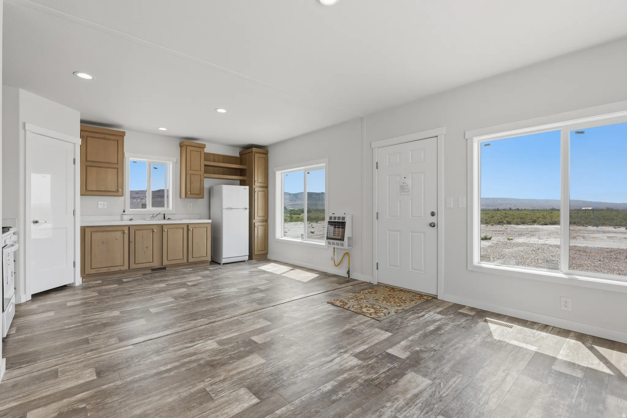Light wood-finish flooring, white walls, wood-finish cabinetry, white countertops, and expansive windows