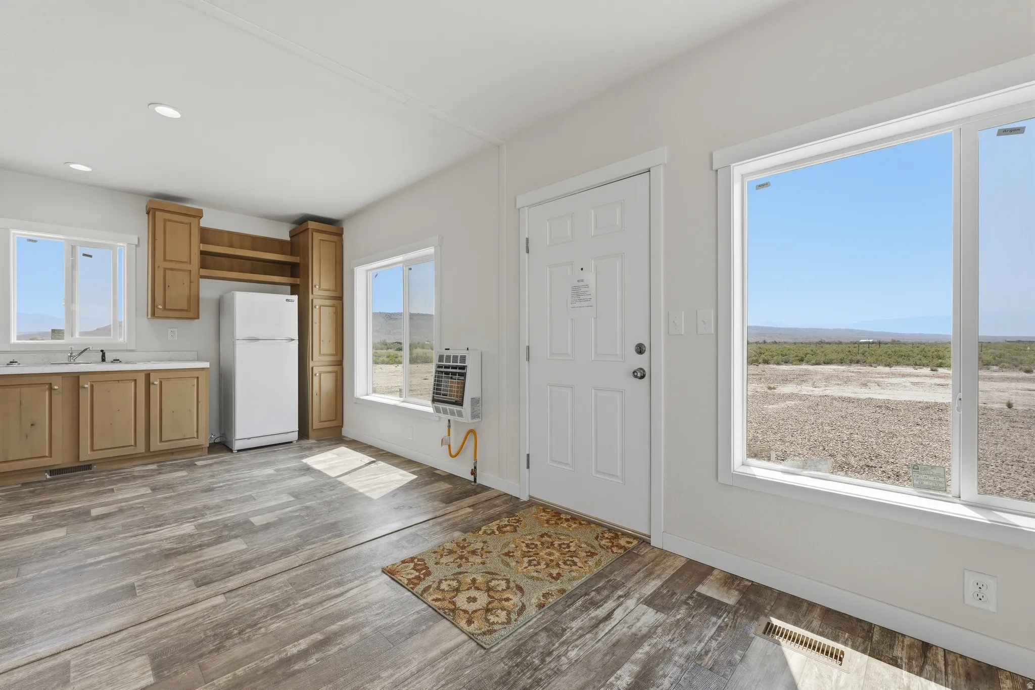 Wood-finish flooring, white walls, recessed lighting, double-pane windows, and a white entry door