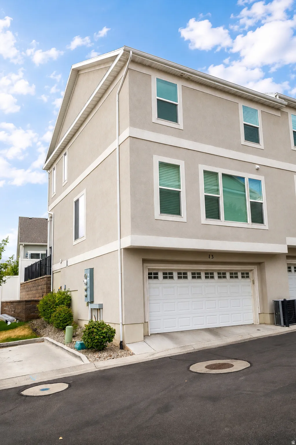 Multi-story exterior with stucco finish, white trim, and a prominent garage door with upper window detailing