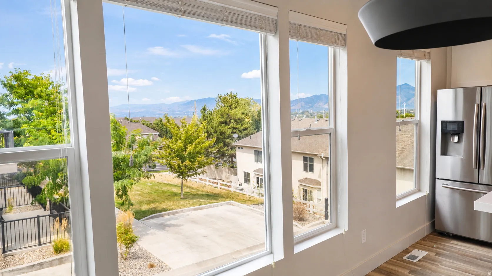 Multiple windows with mountain scenery, a stainless steel refrigerator, and wood-finish flooring