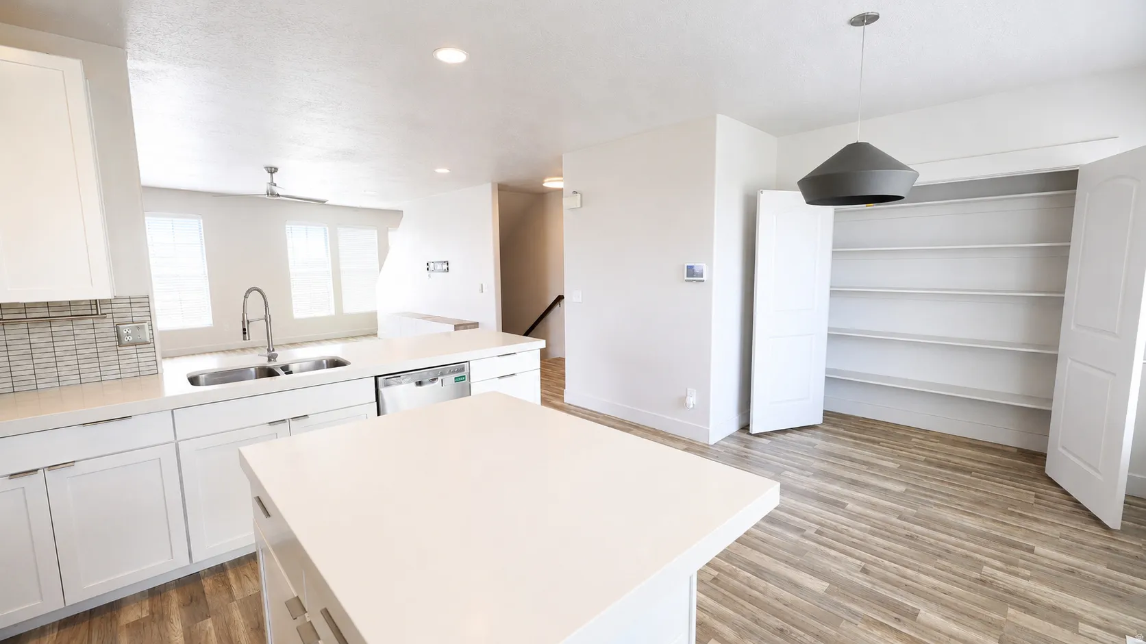 Kitchen featuring a central island, white cabinetry, integrated dishwasher, and a tile backsplash