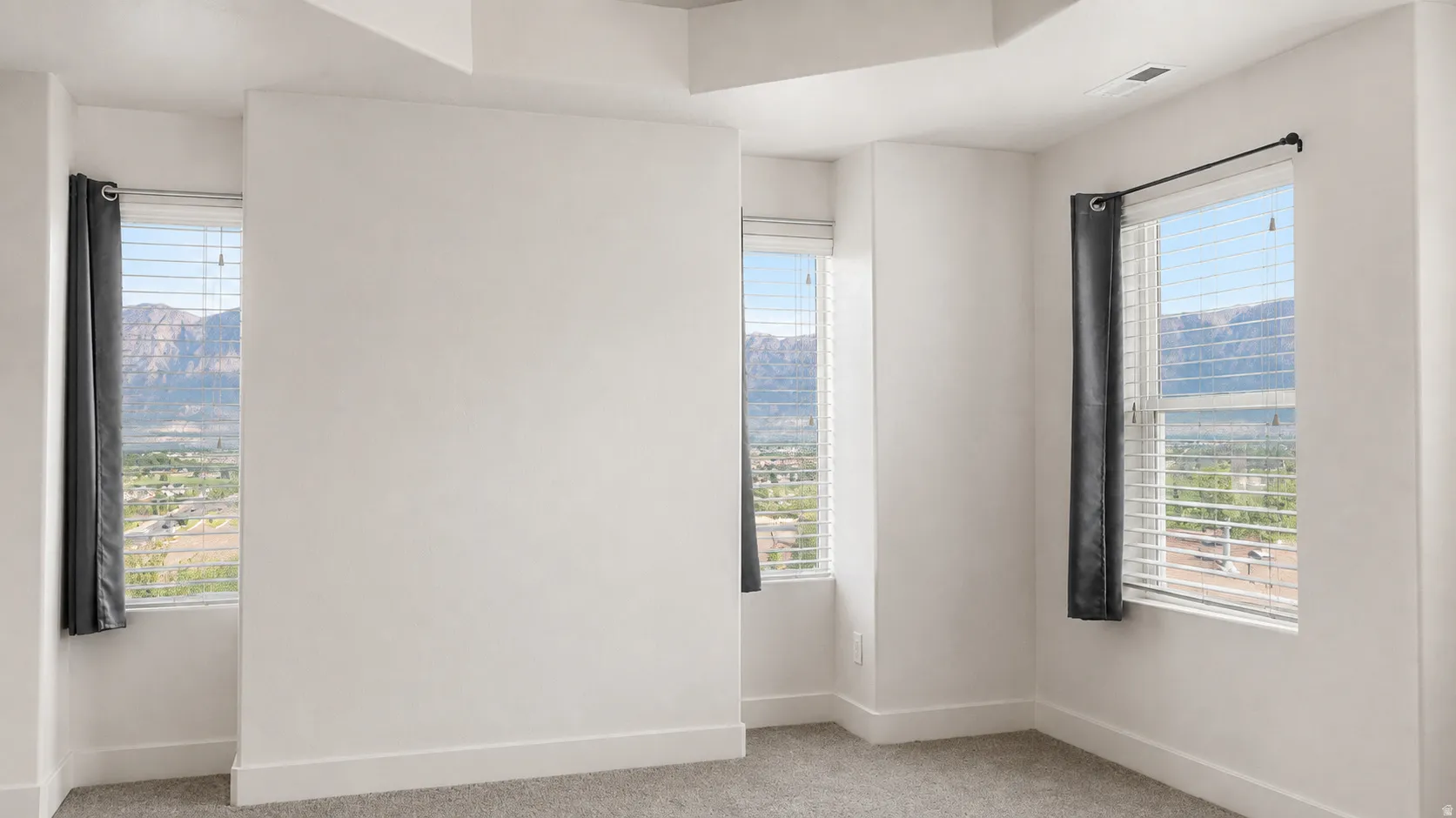 Recessed ceiling, neutral wall paint, gray carpet flooring, and multiple windows with blinds