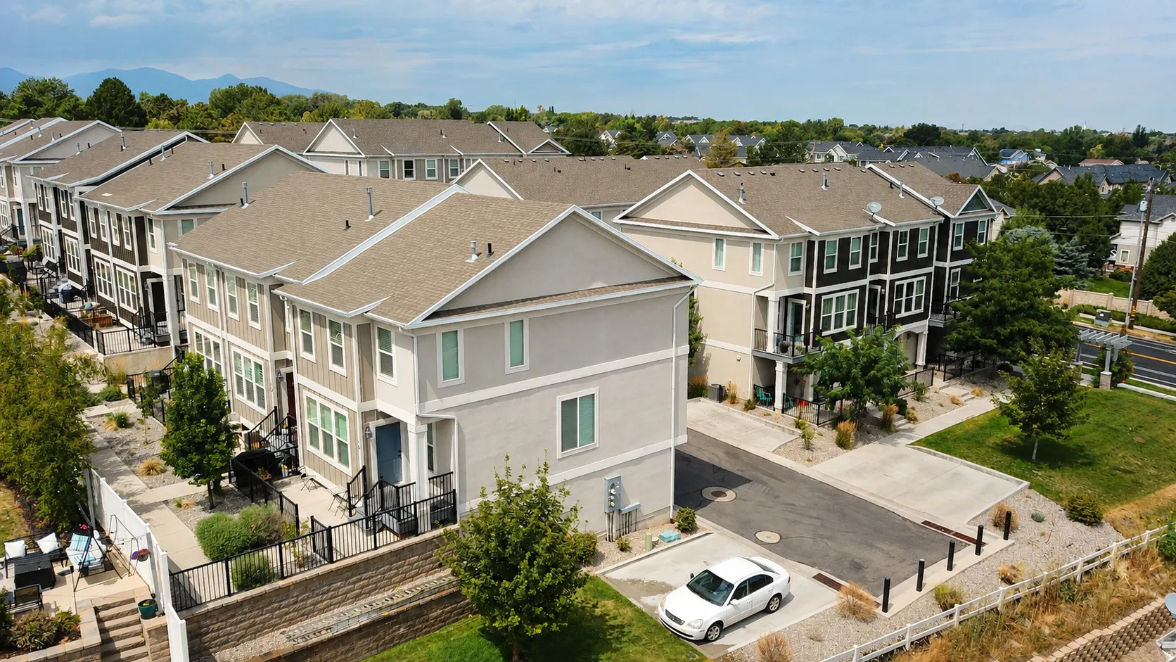 Multiple three-story townhomes featuring neutral-toned siding, asphalt shingle roofs, and individual private outdoor spaces
