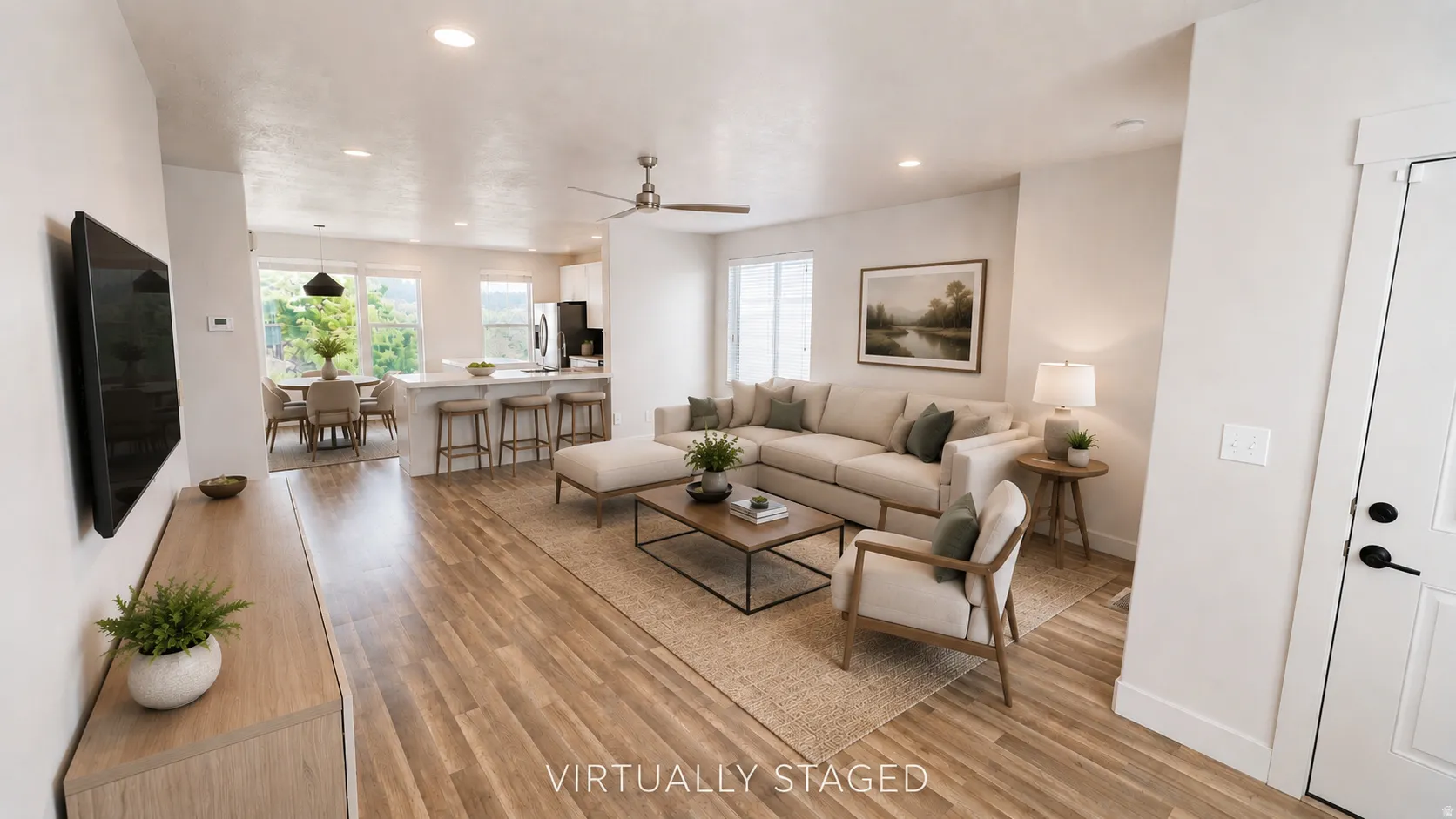 Recessed lighting throughout, wood-finish flooring, ceiling fan, white paneled door with black hardware, and an open-concept layout