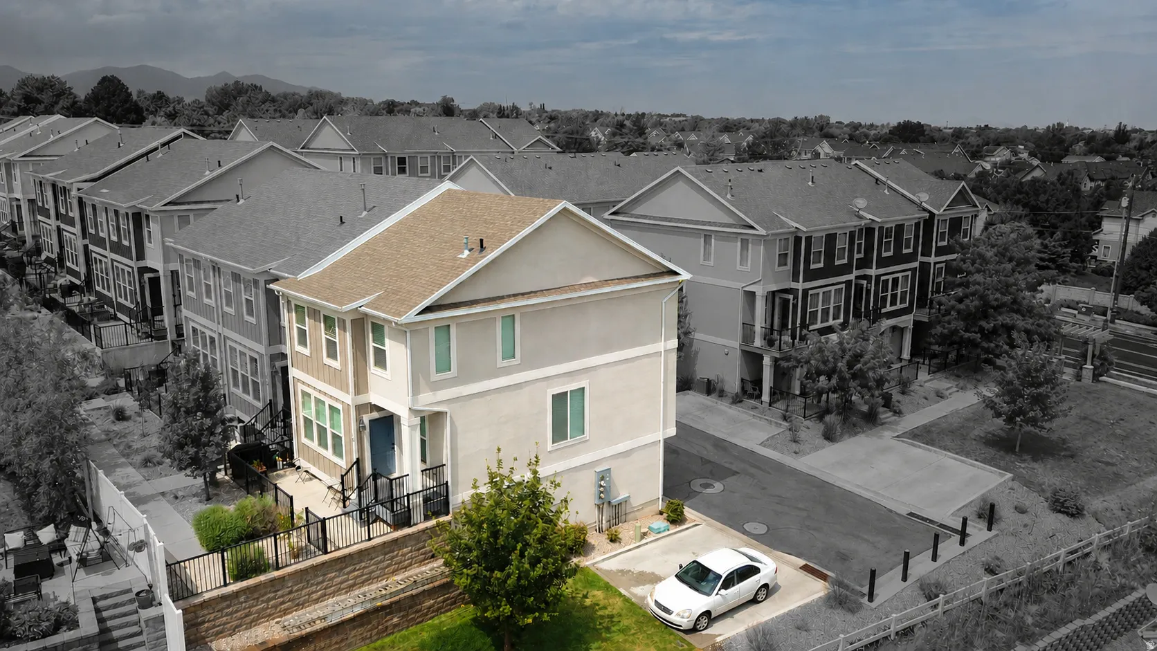 Contemporary stucco and siding exterior with a pitched roof, featuring a vibrant blue entry door and black exterior railings