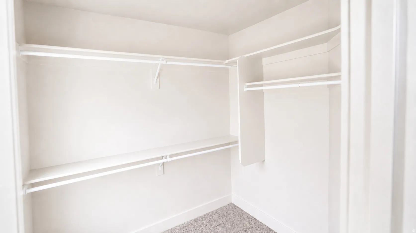 Walk-in closet featuring white wall-mounted shelving and clothing rods