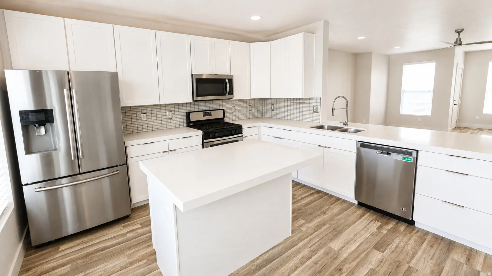 Modern kitchen featuring white cabinetry, stainless steel appliances, a center island, and wood-finish flooring