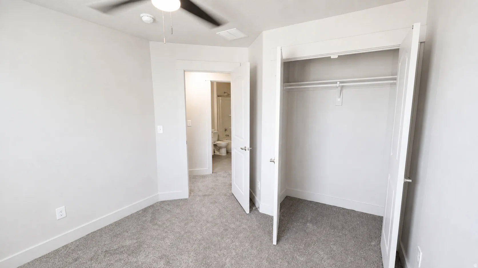 Carpeted flooring, ceiling fan with integrated lighting, and a white bi-fold closet with shelving