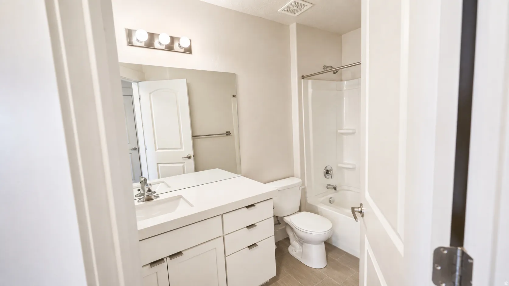 White vanity with brushed nickel hardware, integrated sink, and full-width mirror