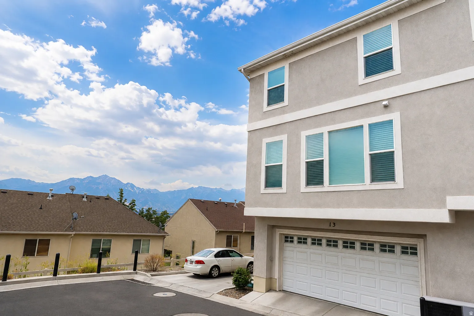 Stucco exterior with multiple windows, an integrated garage, and mountain scenery