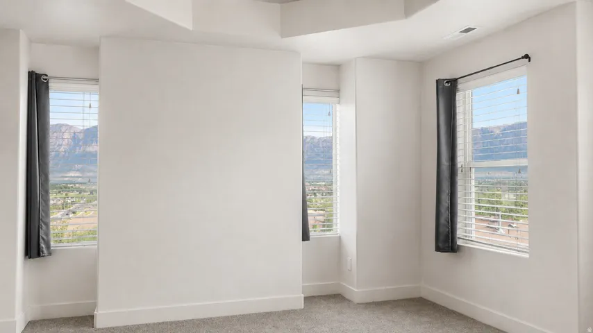 Recessed ceiling, neutral wall paint, gray carpet flooring, and multiple windows with blinds