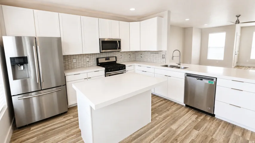 Modern kitchen featuring white cabinetry, stainless steel appliances, a center island, and wood-finish flooring