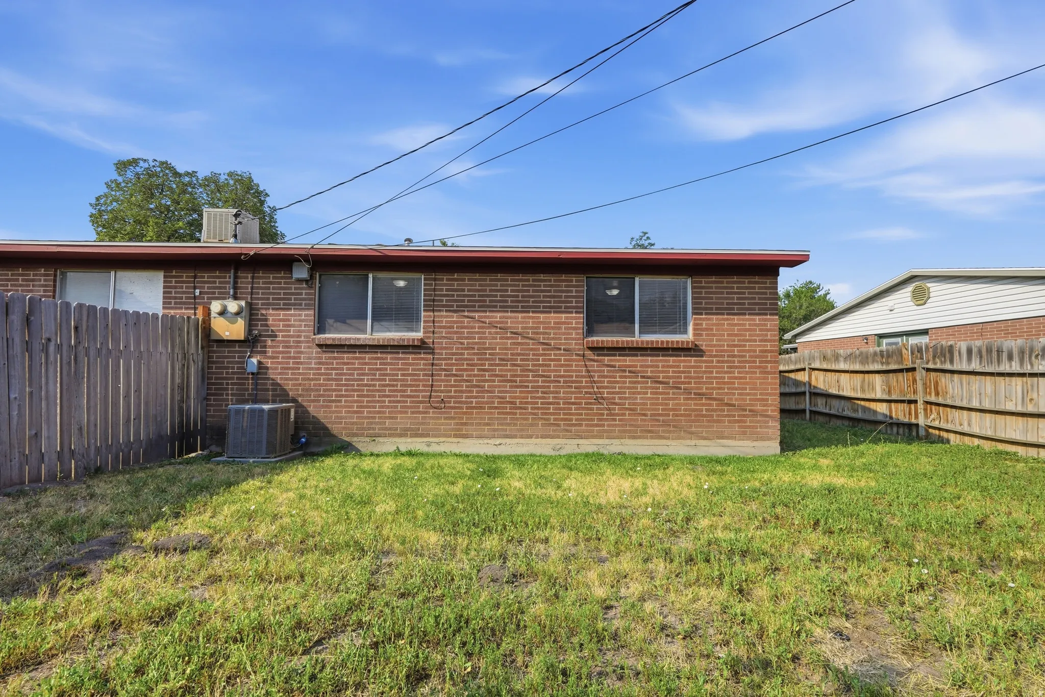 Brick exterior with multiple windows and a wood fence