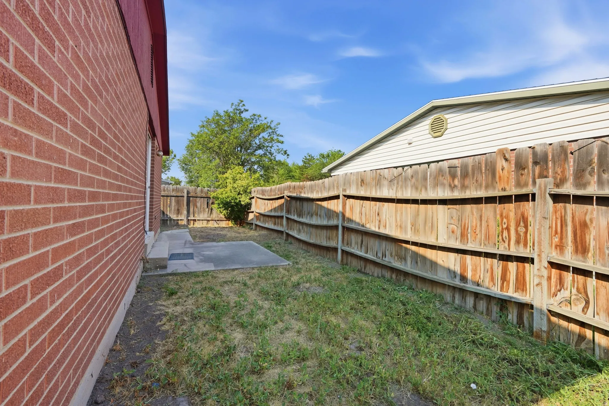 Brick exterior siding, concrete patio, wood privacy fencing