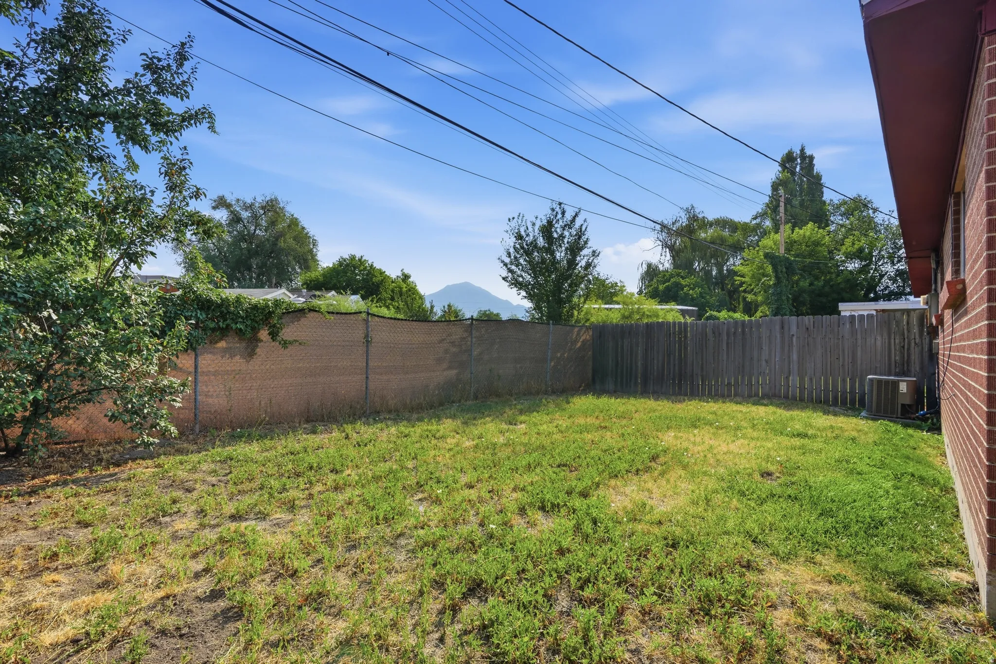 Expansive backyard space with a wood privacy fence and brick exterior