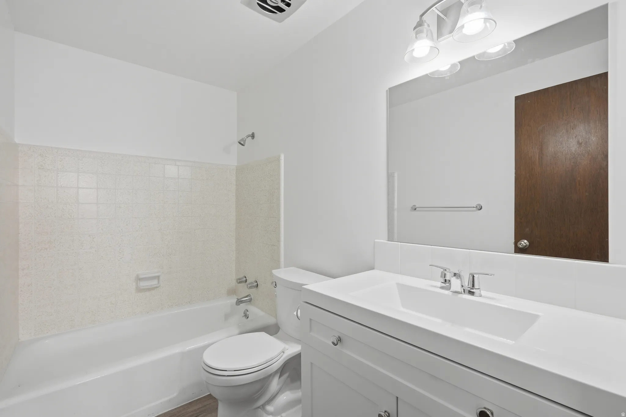 White vanity with integrated sink, chrome faucet, wall-mounted mirror, and overhead lighting