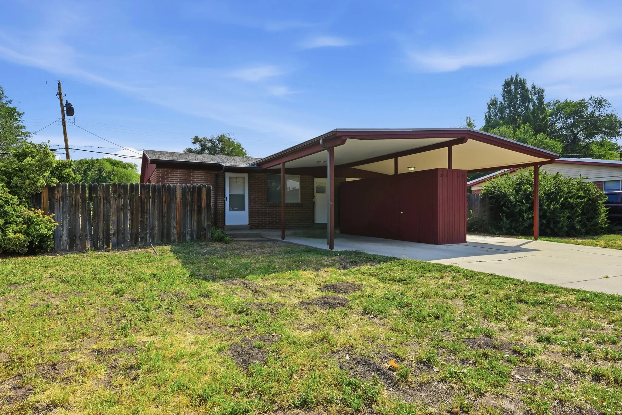 Brick exterior with white trim, covered carport, and a concrete driveway