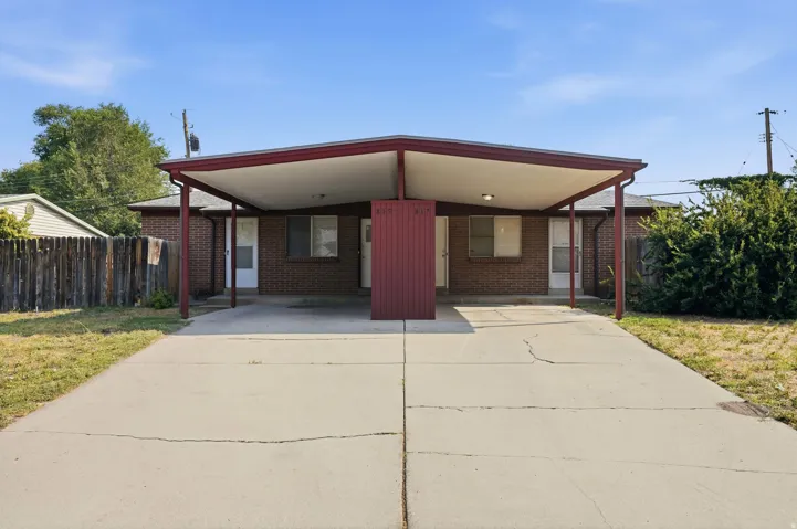 Brick exterior with a covered carport, concrete driveway, and side fencing