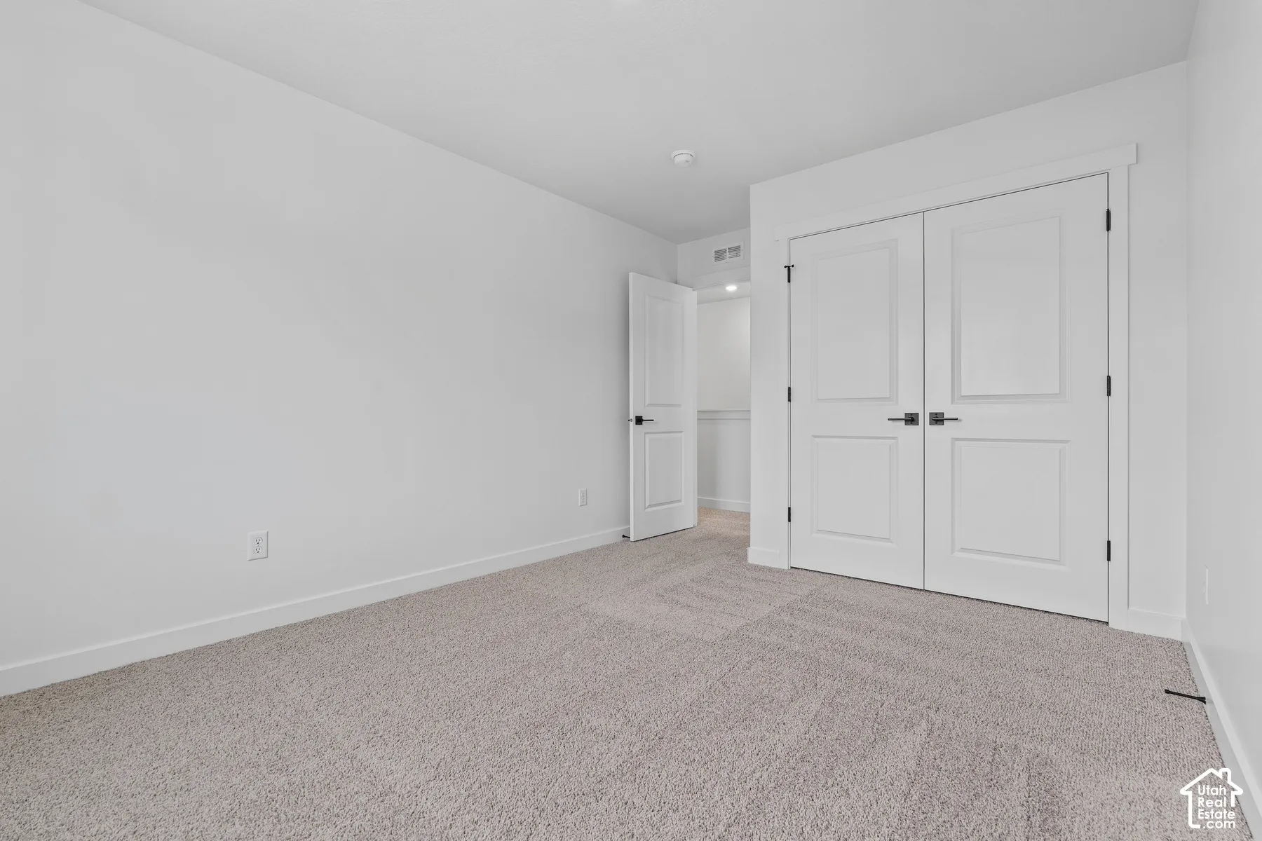 Light-toned carpeting, white walls, and a white ceiling create a bright interior
