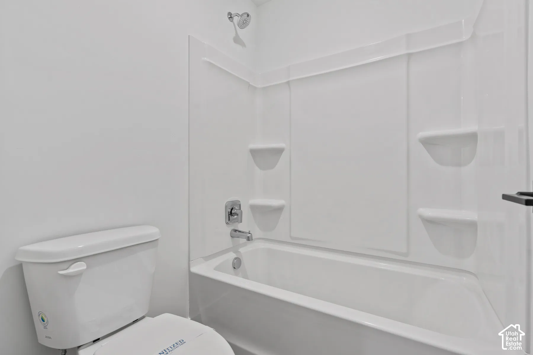 White tub and shower combination with chrome fixtures and integrated shelving