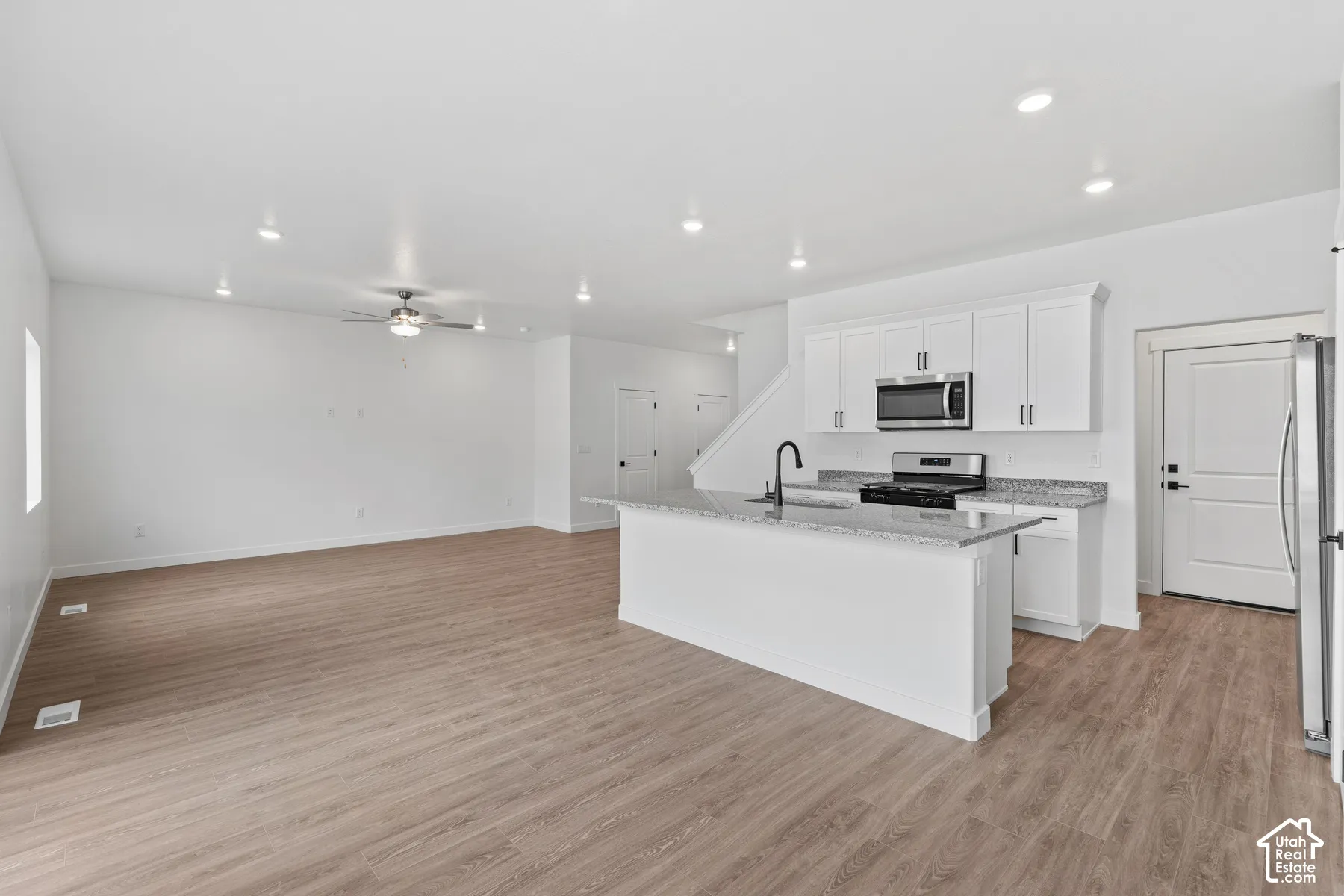 Open-concept living space featuring wood-finish flooring, recessed lighting, and a ceiling fan