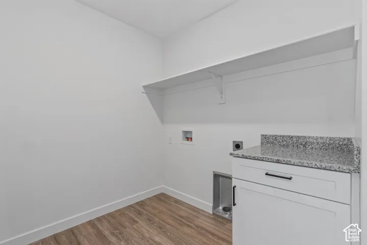 Laundry area with wood-finish flooring, white cabinetry, and a speckled countertop