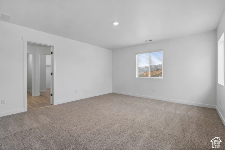 Wall-to-wall carpeting, recessed ceiling lighting, and a single window with horizontal blinds
