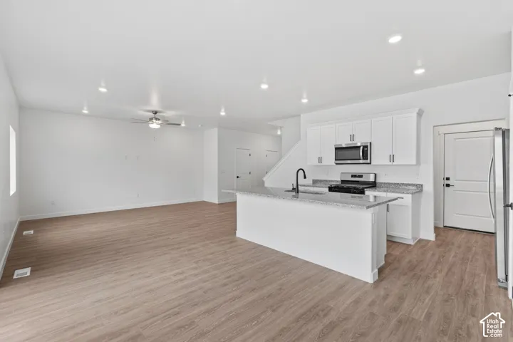 Open-concept living space featuring wood-finish flooring, recessed lighting, and a ceiling fan