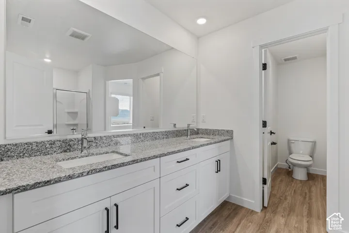 Dual vanity with granite-style countertop, undermount sinks, and white shaker-style cabinetry