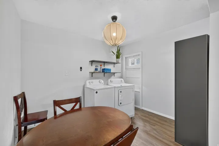 Dedicated laundry area featuring a washer and dryer, wood-finish flooring, and a window for natural light