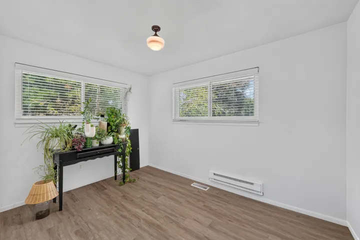 Wood-finish flooring, white walls, and multiple windows with blinds