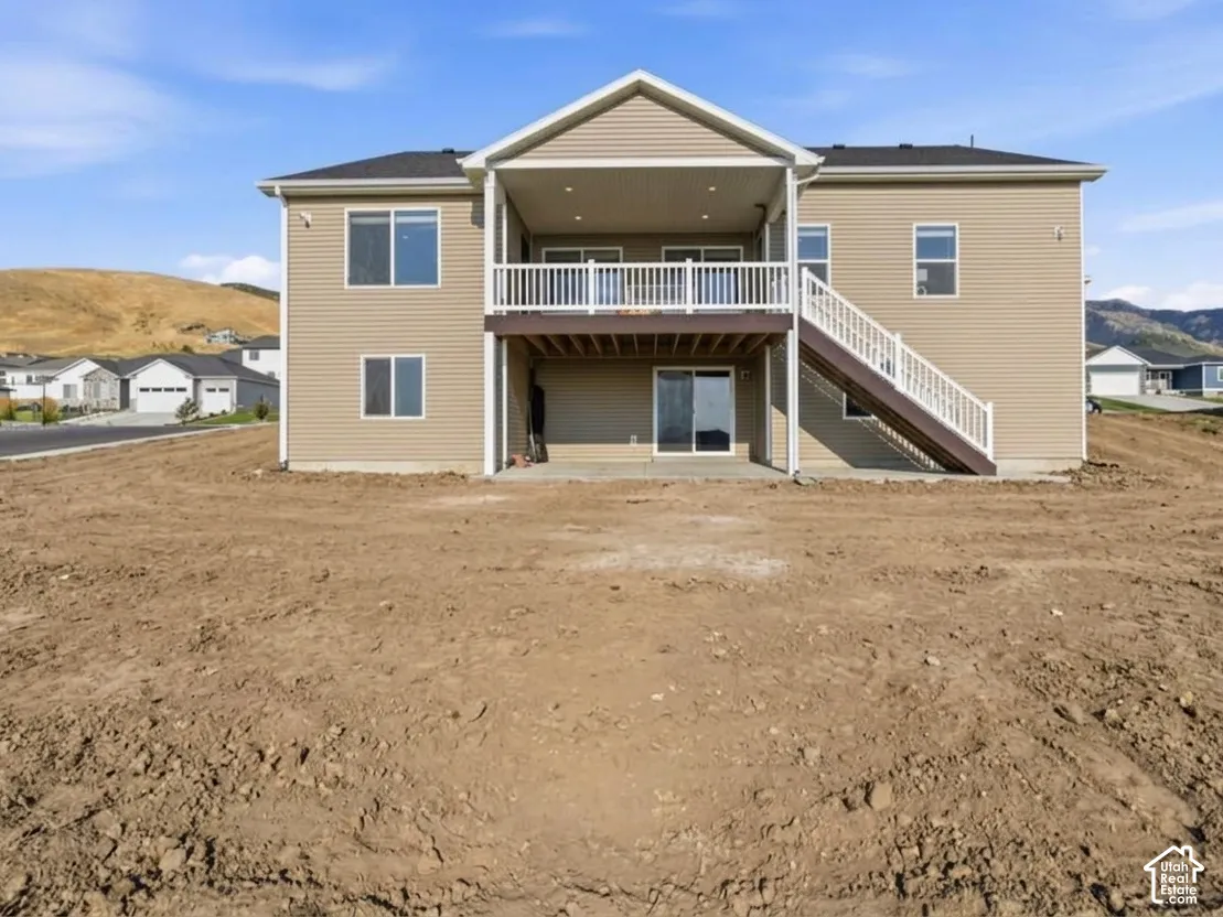 Rear exterior featuring a covered deck, lower patio, and sliding glass door access