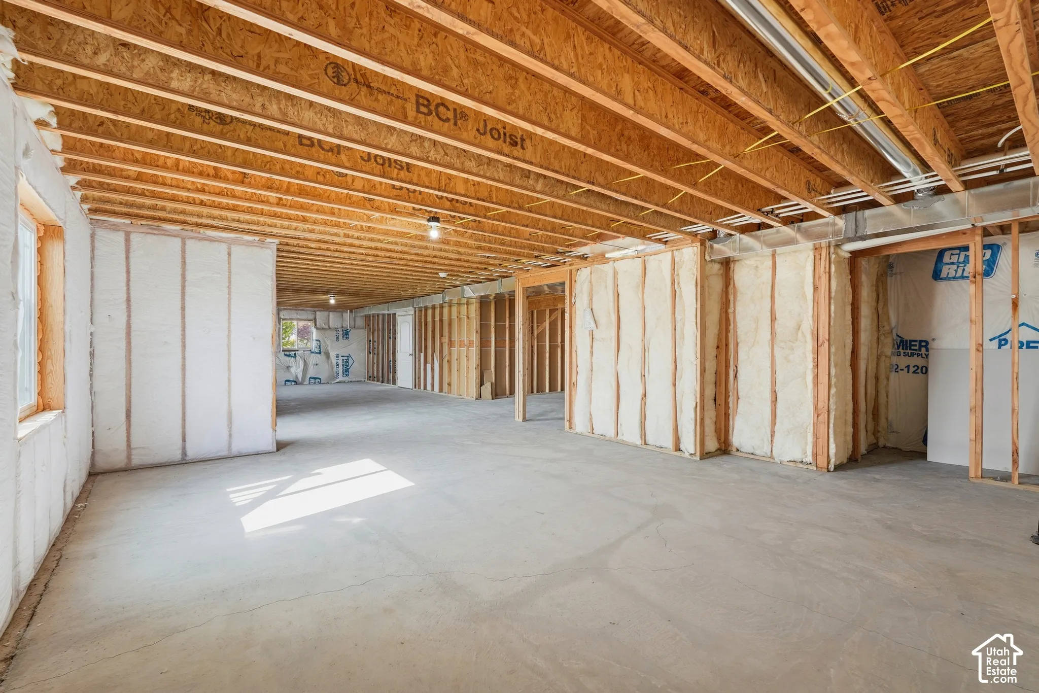 Unfinished open space with exposed wooden joists, framed walls, and concrete flooring
