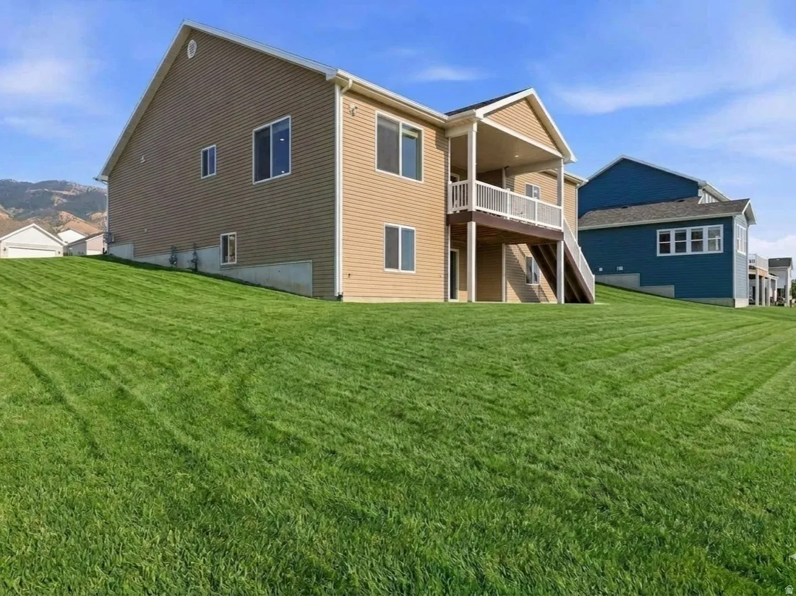 AI GENERATED to give you an idea of what the lawn area could look like, two-story structure, covered balcony, white railing, and visible mountain backdrop