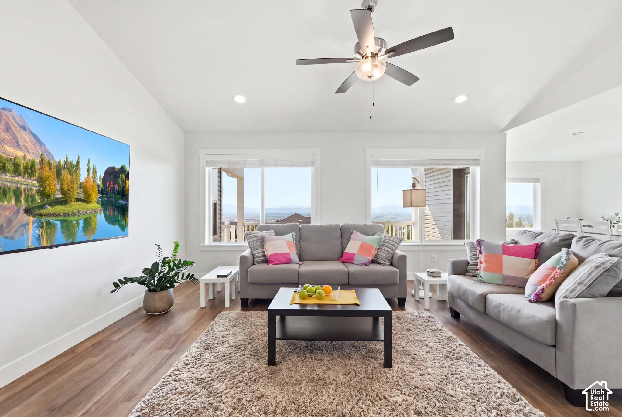 Vaulted ceiling with a ceiling fan, recessed lighting, wood-finish flooring, and large windows