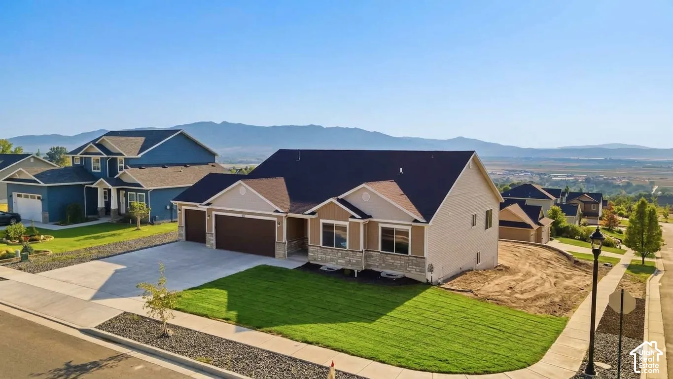 Contemporary home with a stone and siding exterior, a multi-car garage, a concrete driveway, and a manicured lawn