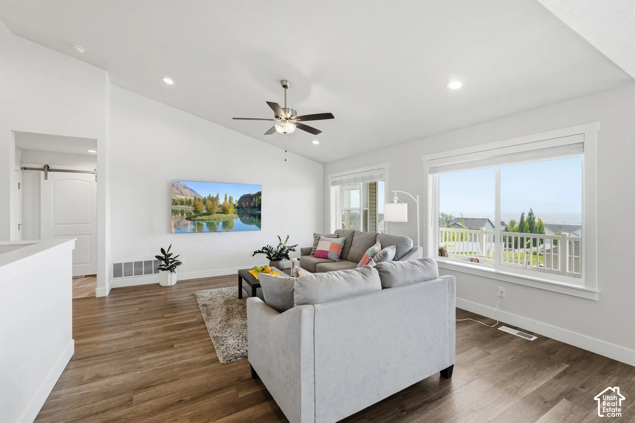 Vaulted ceiling, recessed lighting, wood-finish flooring, ceiling fan, and large windows