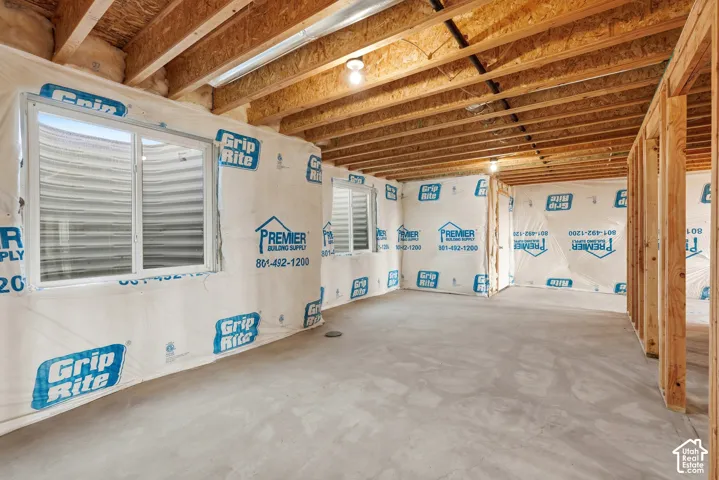 Unfinished lower level with wood framing, exposed ceiling joists, concrete flooring, and multiple egress windows
