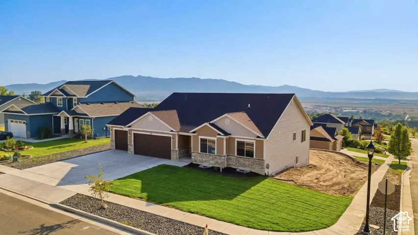 Contemporary home with a stone and siding exterior, a multi-car garage, a concrete driveway, and a manicured lawn