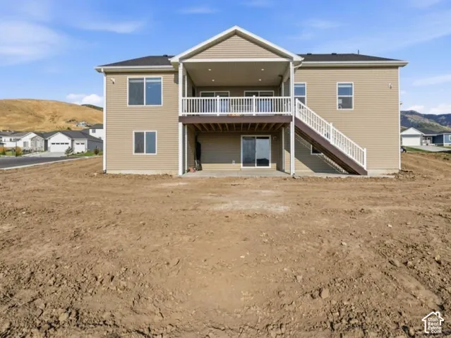 Rear exterior featuring a covered deck, lower patio, and sliding glass door access